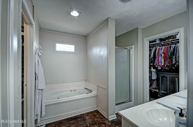 bathroom with a textured ceiling, vanity, and independent shower and bath