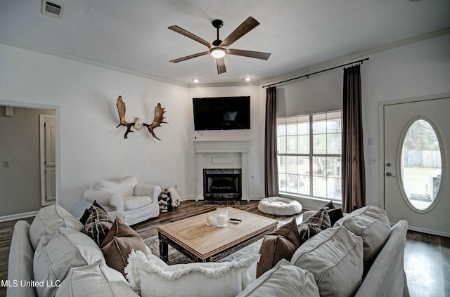 living room with ceiling fan, a high end fireplace, wood-type flooring, and ornamental molding