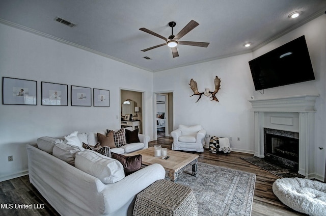 living room with a high end fireplace, wood-type flooring, ceiling fan, and crown molding