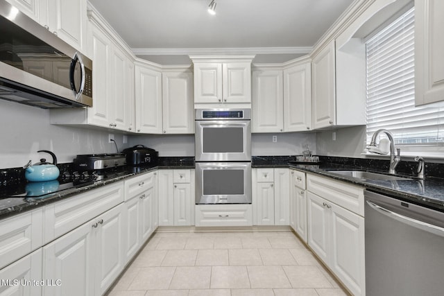 kitchen featuring dark stone countertops, crown molding, white cabinetry, and stainless steel appliances