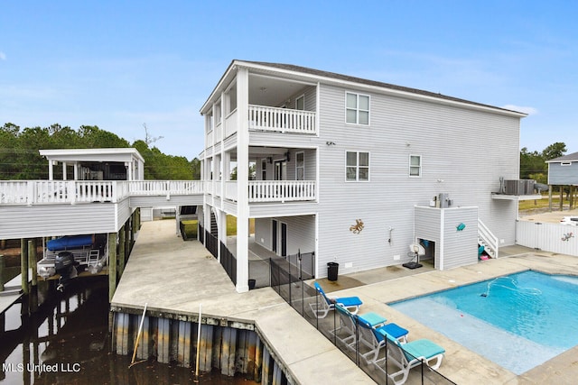 rear view of property featuring a patio area, central AC unit, and a covered pool