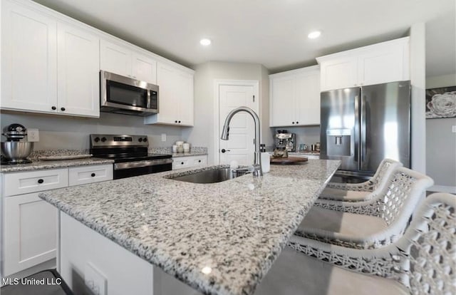 14451 Quail Ridge Dr, Gulfport, MS 39503 - kitchen featuring stainless steel appliances, a sink, white cabinets, a kitchen breakfast bar, and an island with sink