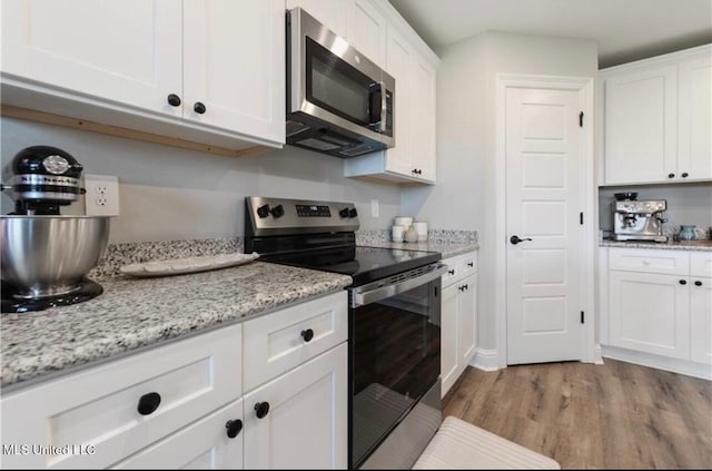 14451 Quail Ridge Dr, Gulfport, MS 39503 - kitchen with stainless steel appliances, wood finished floors, white cabinets, and light stone counters