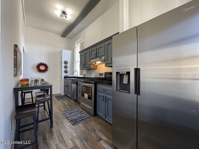 1116 Main St, Natchez, MS 39120 - kitchen with under cabinet range hood, stainless steel appliances, dark countertops, and dark wood finished floors