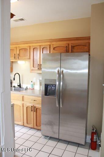 1116 Main St, Natchez, MS 39120 - kitchen with visible vents, stainless steel fridge with ice dispenser, light countertops, light tile patterned flooring, and a sink