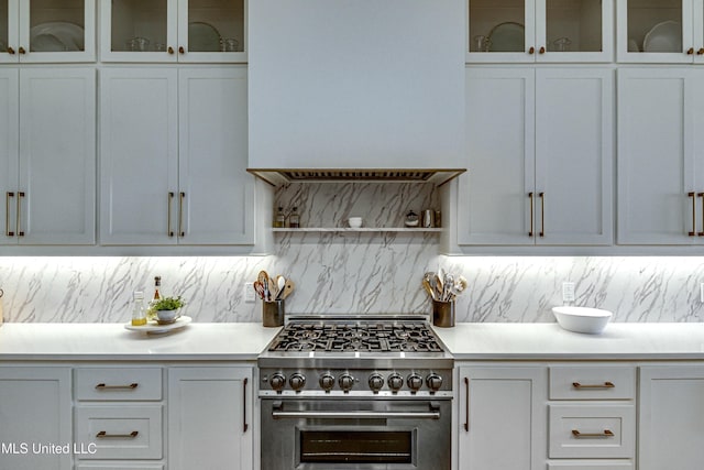 kitchen with white cabinetry, stainless steel stove, and backsplash