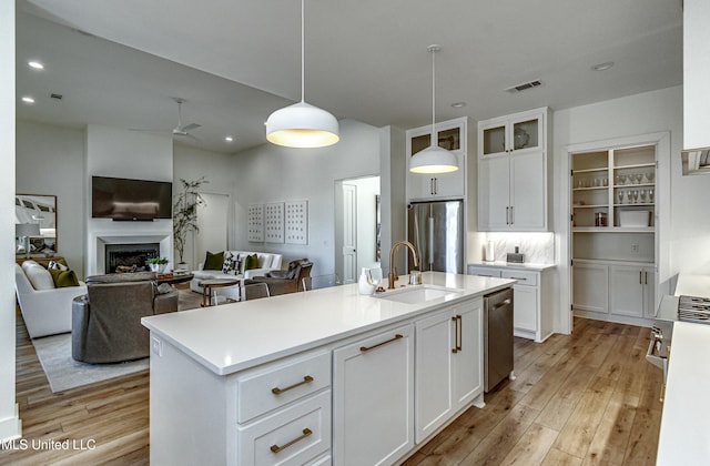 kitchen with sink, white cabinetry, appliances with stainless steel finishes, an island with sink, and pendant lighting