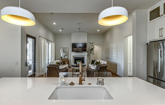 kitchen featuring white cabinetry, decorative light fixtures, high end fridge, and sink