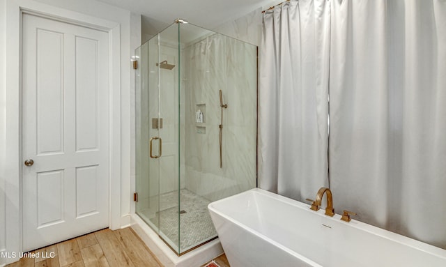 bathroom featuring wood-type flooring and shower with separate bathtub