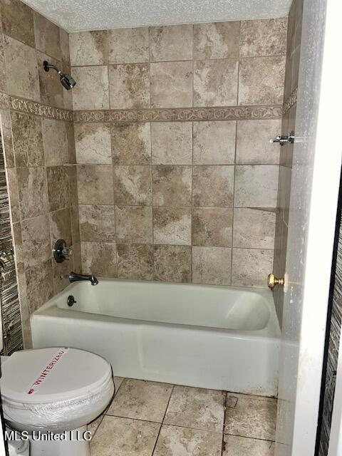 bathroom with tiled shower / bath combo, tile patterned floors, and a textured ceiling