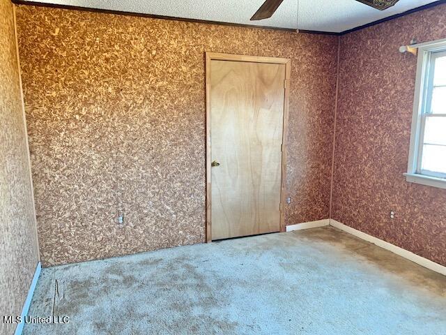 unfurnished bedroom with multiple windows, crown molding, ceiling fan, and carpet