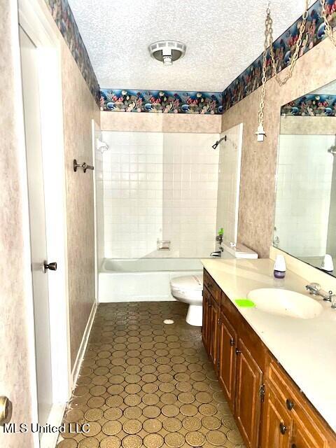 full bathroom with tiled shower / bath combo, vanity, a textured ceiling, and toilet