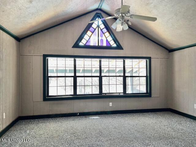 spare room with ceiling fan, lofted ceiling, and wooden walls