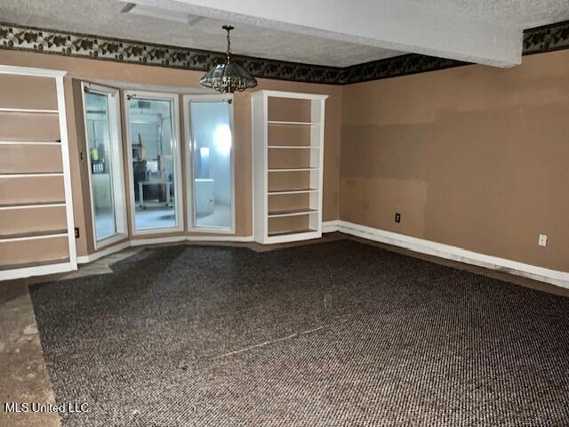 empty room with built in features and a textured ceiling