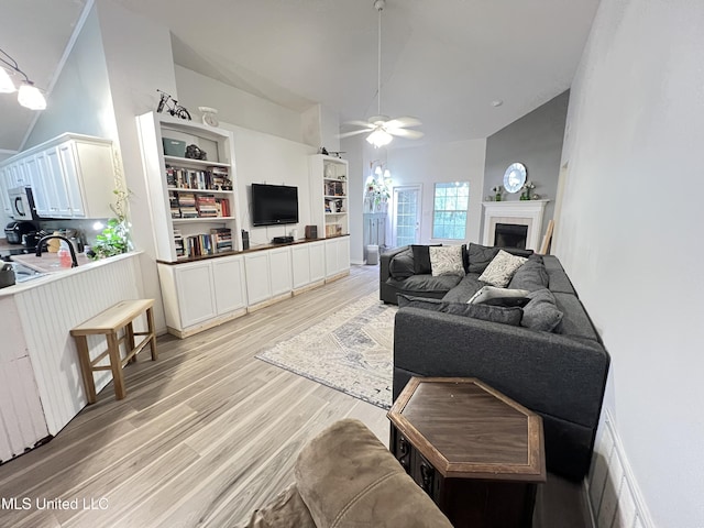 9929 Kahana St, Diamondhead, MS 39525 - living area featuring ceiling fan, light wood finished floors, a tiled fireplace, and high vaulted ceiling