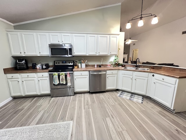 9929 Kahana St, Diamondhead, MS 39525 - kitchen featuring stainless steel appliances, white cabinets, a peninsula, light wood-style flooring, and hanging light fixtures