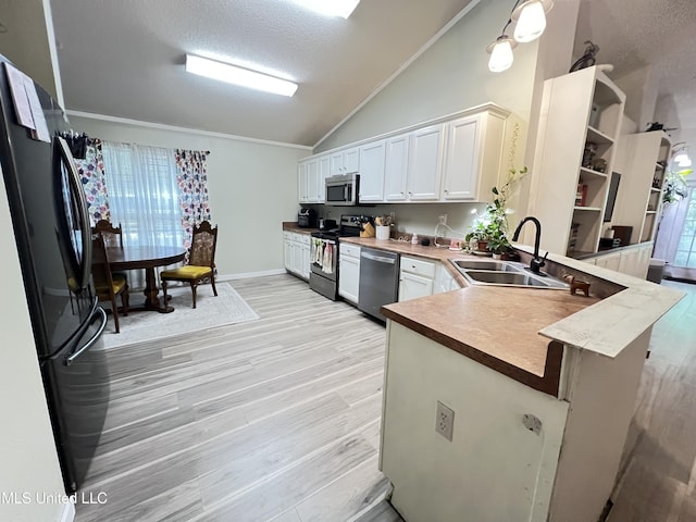 9929 Kahana St, Diamondhead, MS 39525 - kitchen featuring stainless steel appliances, vaulted ceiling, open shelves, light wood-style floors, and white cabinets