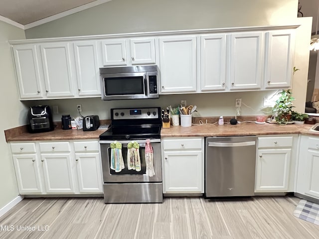 9929 Kahana St, Diamondhead, MS 39525 - kitchen featuring appliances with stainless steel finishes, crown molding, white cabinets, light wood-style flooring, and vaulted ceiling
