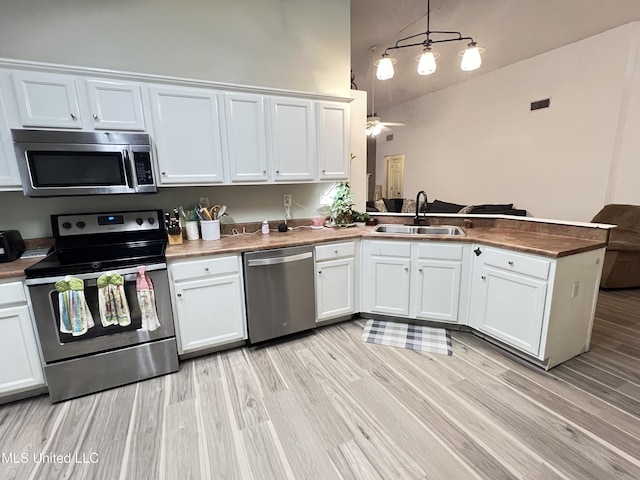 9929 Kahana St, Diamondhead, MS 39525 - kitchen with appliances with stainless steel finishes, a peninsula, white cabinets, light wood-style floors, and lofted ceiling