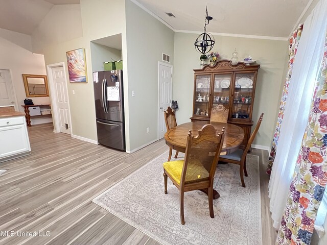 9929 Kahana St, Diamondhead, MS 39525 - dining room featuring light wood-style flooring, crown molding, and vaulted ceiling