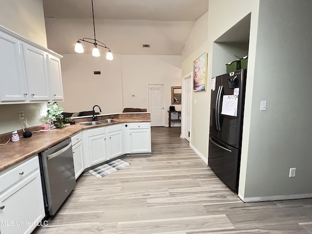 9929 Kahana St, Diamondhead, MS 39525 - kitchen with freestanding refrigerator, stainless steel dishwasher, a peninsula, vaulted ceiling, and white cabinetry