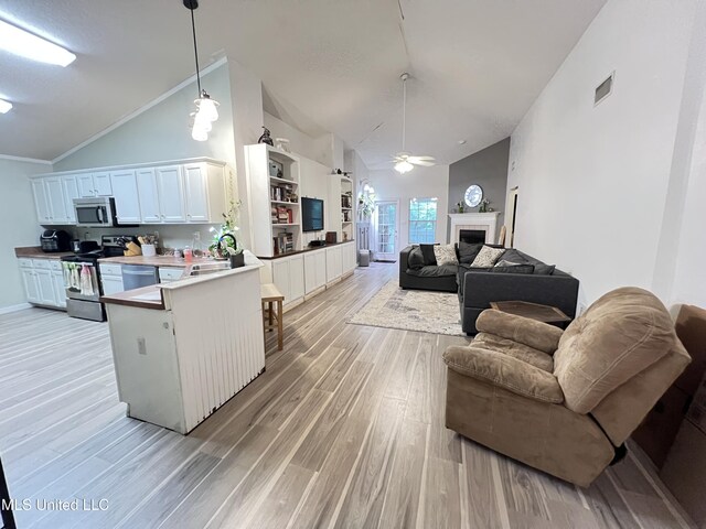 9929 Kahana St, Diamondhead, MS 39525 - kitchen with appliances with stainless steel finishes, open floor plan, light wood finished floors, a ceiling fan, and high vaulted ceiling