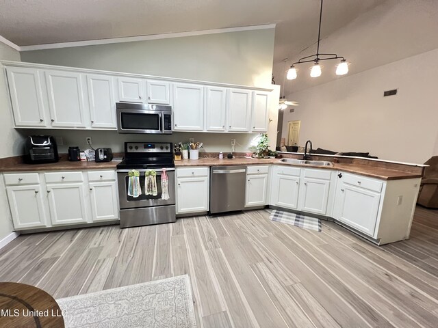 9929 Kahana St, Diamondhead, MS 39525 - kitchen with stainless steel appliances, a peninsula, white cabinets, light wood-style flooring, and high vaulted ceiling
