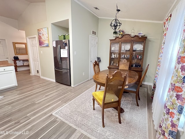 9929 Kahana St, Diamondhead, MS 39525 - dining room featuring light wood-style flooring, crown molding, and vaulted ceiling