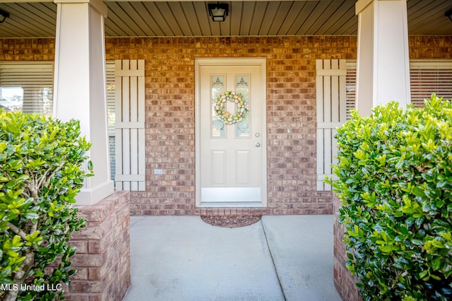 entrance to property with brick siding and a porch