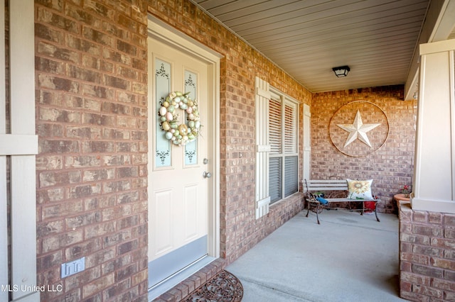 property entrance featuring brick siding and a porch