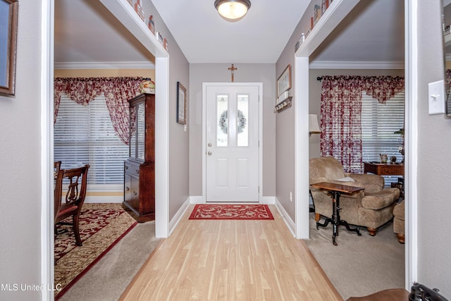foyer with light wood-style flooring, baseboards, and ornamental molding