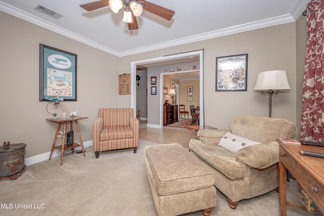 living room with baseboards, crown molding, visible vents, ceiling fan, and light colored carpet