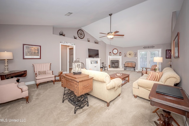 living room featuring a glass covered fireplace, visible vents, ceiling fan, high vaulted ceiling, and light colored carpet