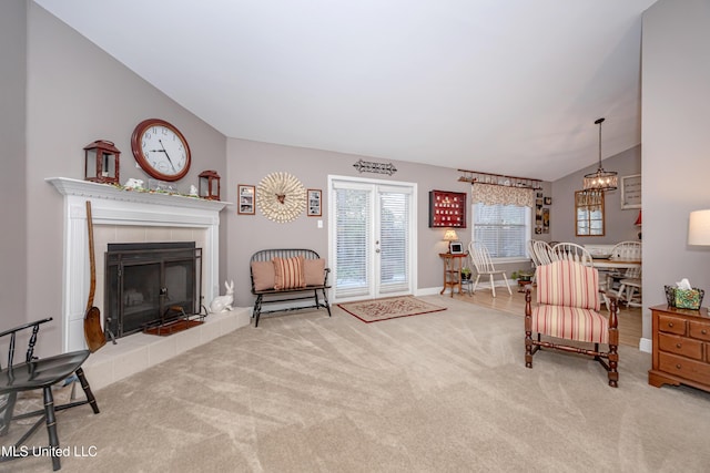 carpeted living room with a healthy amount of sunlight, a fireplace, a notable chandelier, and lofted ceiling