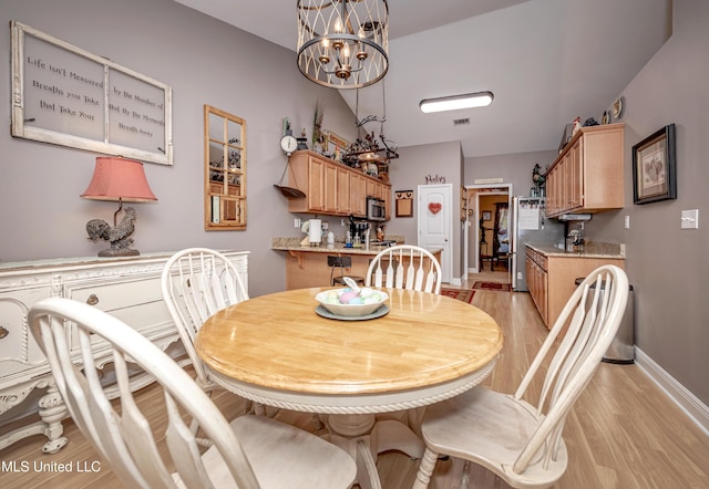dining area featuring a chandelier, light wood-style flooring, baseboards, and visible vents