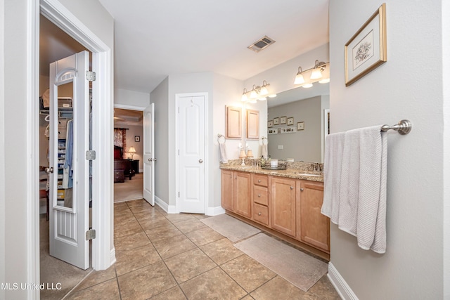 full bathroom featuring visible vents, a sink, a walk in closet, tile patterned floors, and double vanity