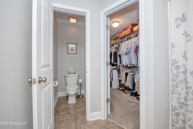 full bath featuring baseboards, a spacious closet, tile patterned flooring, a shower with curtain, and toilet