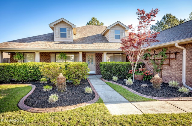 view of front of house with brick siding, a front yard, and a shingled roof