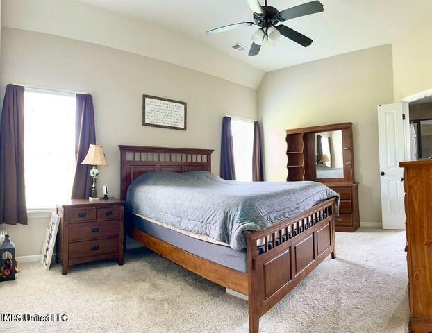 bedroom featuring ceiling fan, baseboards, vaulted ceiling, and light colored carpet