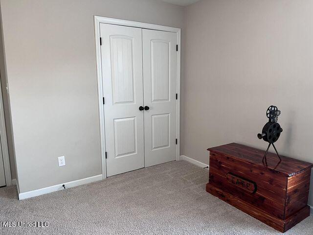 carpeted bedroom featuring a closet and baseboards