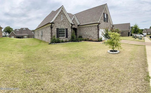 french provincial home with a garage, a front lawn, and brick siding