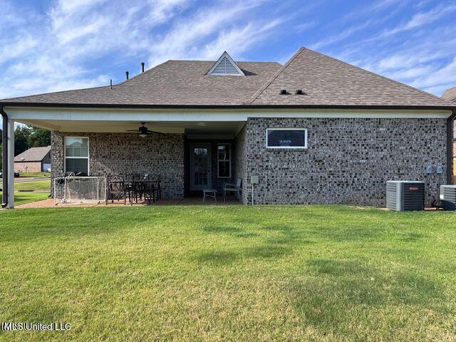 back of property featuring central AC, a ceiling fan, a yard, roof with shingles, and a patio area