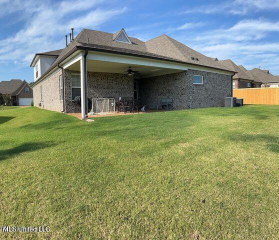 back of property with ceiling fan, brick siding, fence, a yard, and a patio area