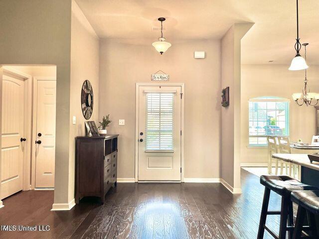 foyer entrance featuring a chandelier, dark wood-style flooring, and baseboards