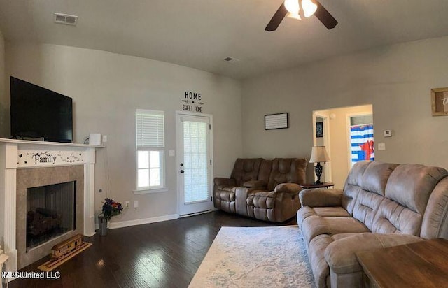 living area with a tile fireplace, dark wood-style flooring, visible vents, and ceiling fan