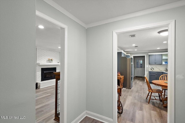 hallway with crown molding and light hardwood / wood-style flooring