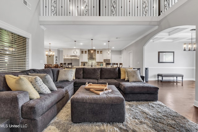 living area featuring a chandelier, arched walkways, dark wood finished floors, beam ceiling, and recessed lighting