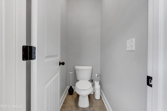 bathroom with toilet, baseboards, and tile patterned floors