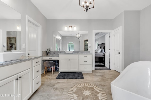 bathroom featuring vanity, a soaking tub, a chandelier, and ensuite bath