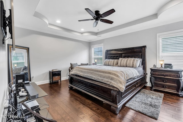 bedroom featuring a raised ceiling, crown molding, hardwood / wood-style flooring, recessed lighting, and baseboards